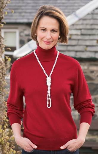 brunette model in red merino roll neck wearing string of pearls